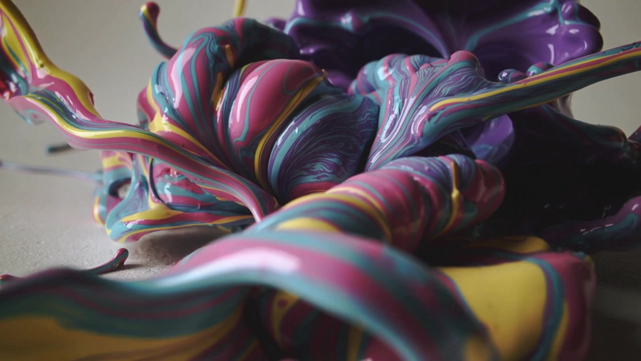 Starting low paint mound spreading outward, pink purple teal ribbons unfurling on neutral tabletop