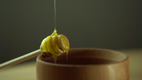 thick honey dripping from the spoon, close up. honey flowing honey from a spoon