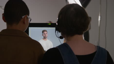 female film director and assistant watching actor on monitor shooting movie or video scene in studio shot in real time 1