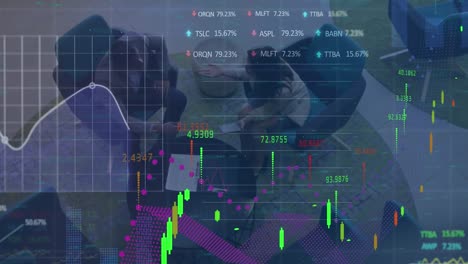 Animation-of-graphs,-trading-boards,-high-angle-view-of-diverse-coworkers-sharing-ideas-in-office