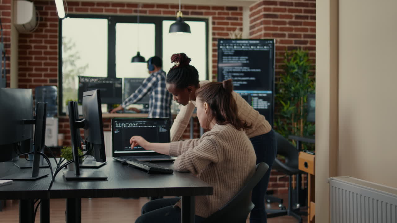 Two software coders analyzing source code looking for errors running on laptop screen