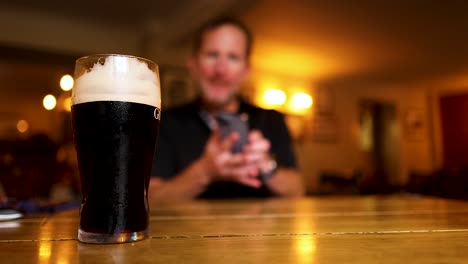 man reaching for a pint of stout beer