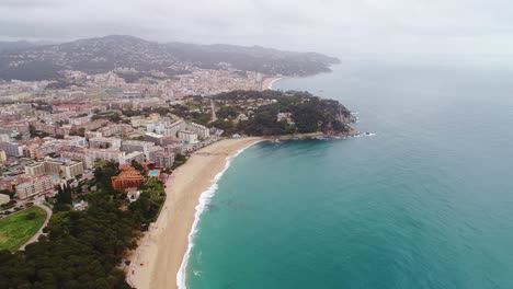 drone captures scenic lloret de mar coast with mountains, buildings, blue sea