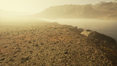 un río claro con rocas conduce hacia las montañas iluminadas por la puesta de sol