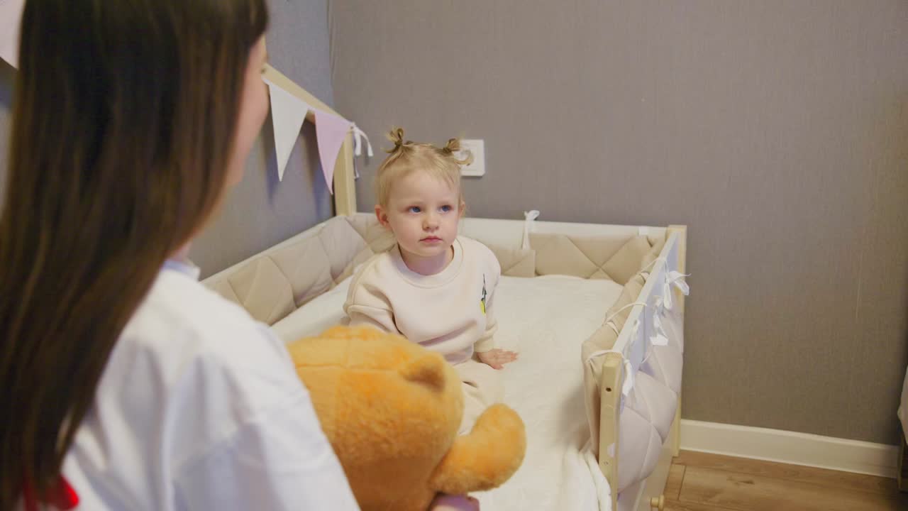 Mamma che gioca con un bambino felice nella culla a casa