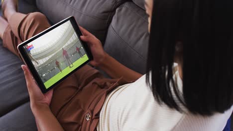 Zusammensetzung-Einer-Frau-Auf-Der-Couch-Zu-Hause,-Die-Sich-Ein-Rugbyspiel-Auf-Einem-Tablet-Ansieht