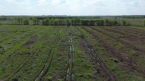 aerial view of muddy forest clearing with deep tire tracks cutting through the deforested area.