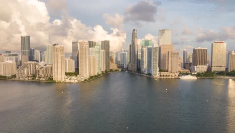 Luftbild-Hyperrafferaufnahme-Der-Skyline-Von-Miamis-Innenstadt-Bei-Sonnenaufgang-Am-Morgen-Mit-Hoch-Aufragenden-Wolkenkratzern-Entlang-Der-Uferpromenade,-Klarem-Himmel-Und-Spiegelungen-Auf-Dem-Wasser