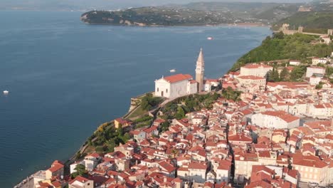 drone shot and dolly zoom of church in piran, slovenia. ancient catholic church on top of the cliff with adriatic sea in the background.