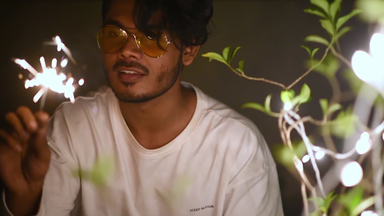 쾌활한 젊은 아시아 남성이 디왈리, 크리스마스, 새해를 기념하기 위해 불꽃놀이와 폭죽을 가지고 노는 슬로우 모션