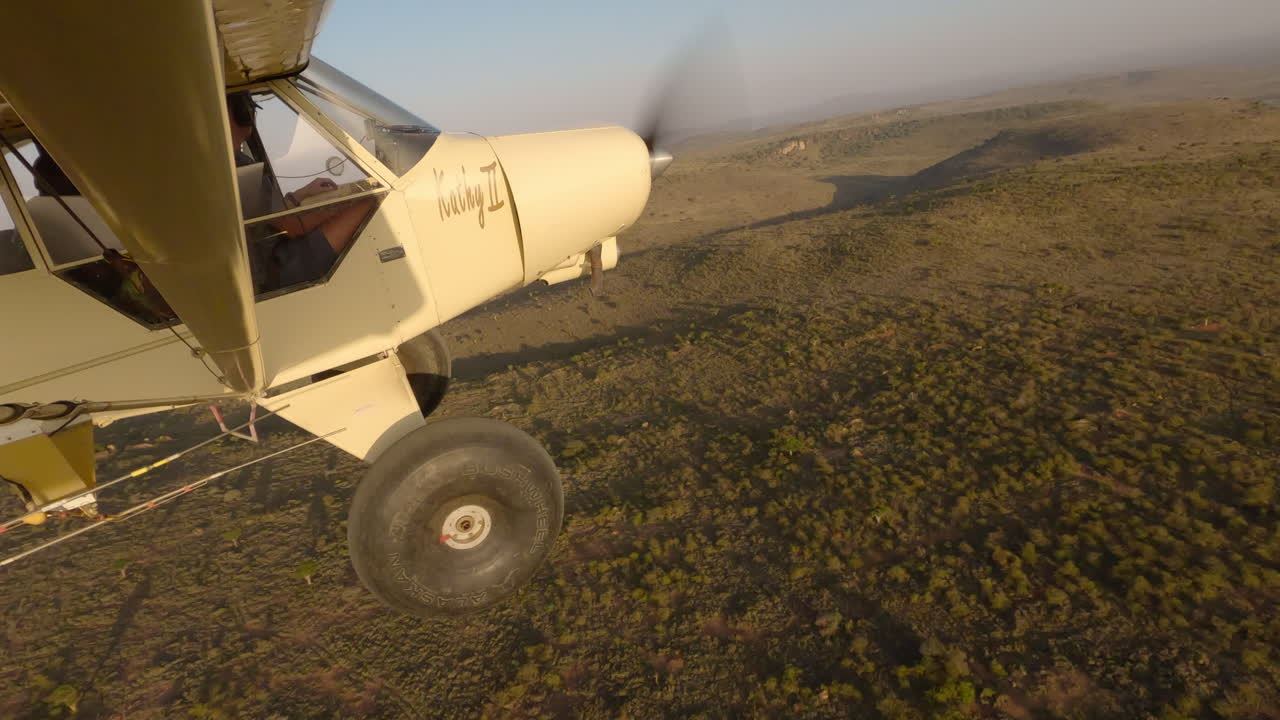 Plane over aerial of valley and vegetation with shadow