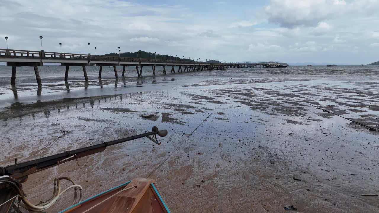 Aerial view of longtail boats at a fishing dock during low tide in Phuket, Thailand, showcasing serene coastal scenery