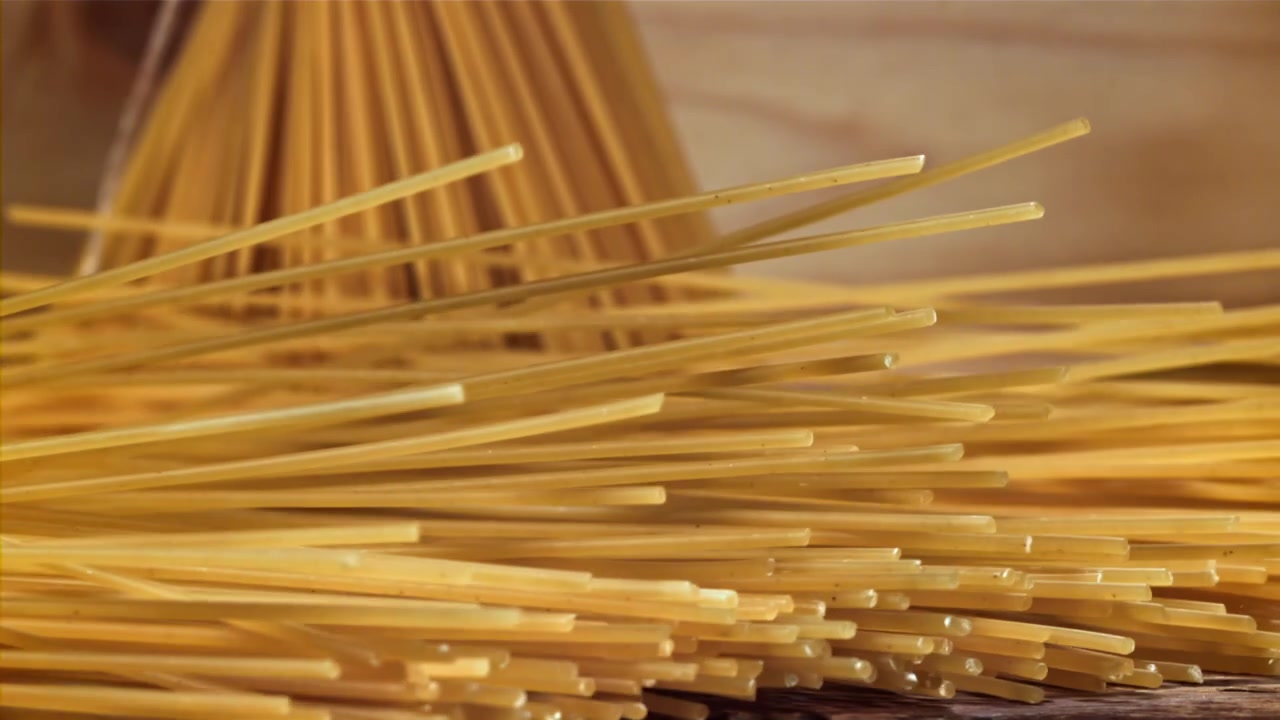 Primo piano di spaghetti secchi che cadono su un tavolo di legno
