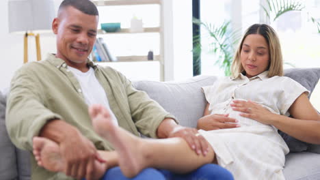 man rub his pregnant wife feet while relaxing