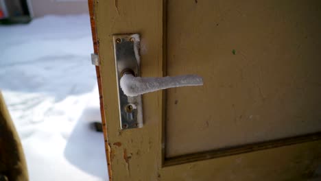 a brown door with the door knob covered with ice