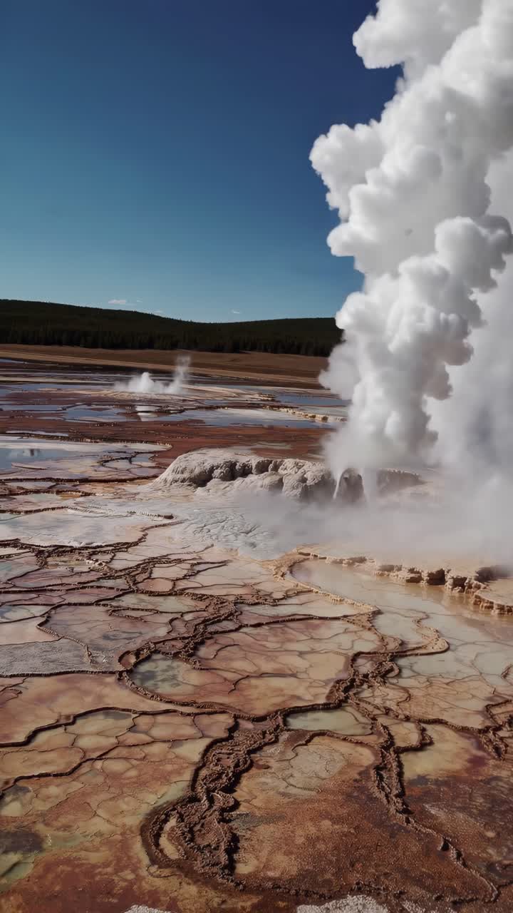Luftaufnahme eines dampfenden Geysirs in einer weitläufigen, felsigen Landschaft