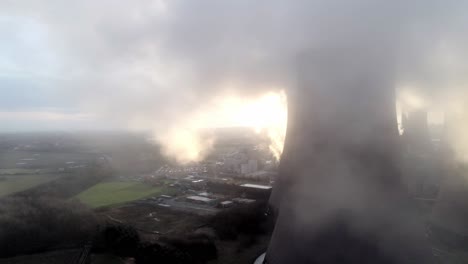 aerial view of atmospheric uk power station cooling towers through smoke steam emissions at sunrise