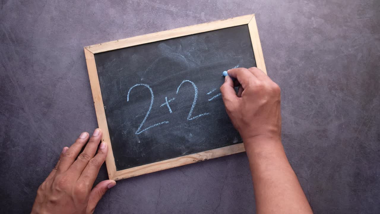 persona escribiendo 2+2 en una pizarra