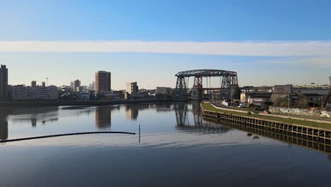 Wide-aerial-pan-of-Puente-Transbordador-and-still-water,-Buenos-Aires