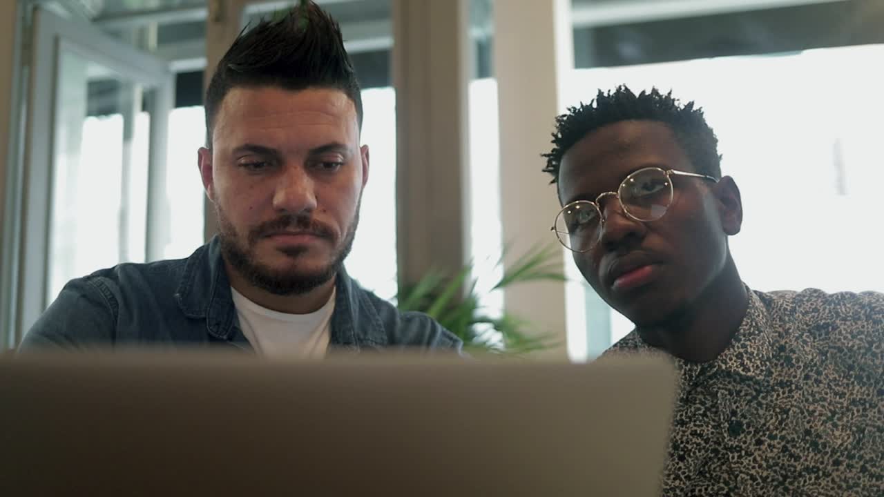 Concentrated young men using laptop in coffee shop