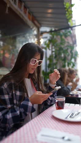 woman using phone in outdoor cafe