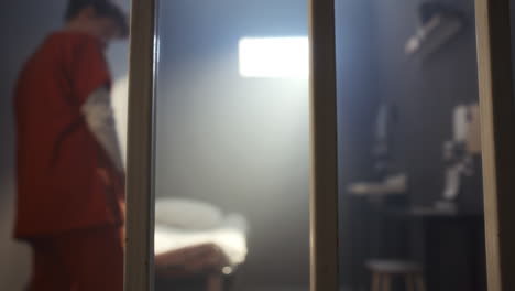 close-up of prison cell bars with inmate walking behind them