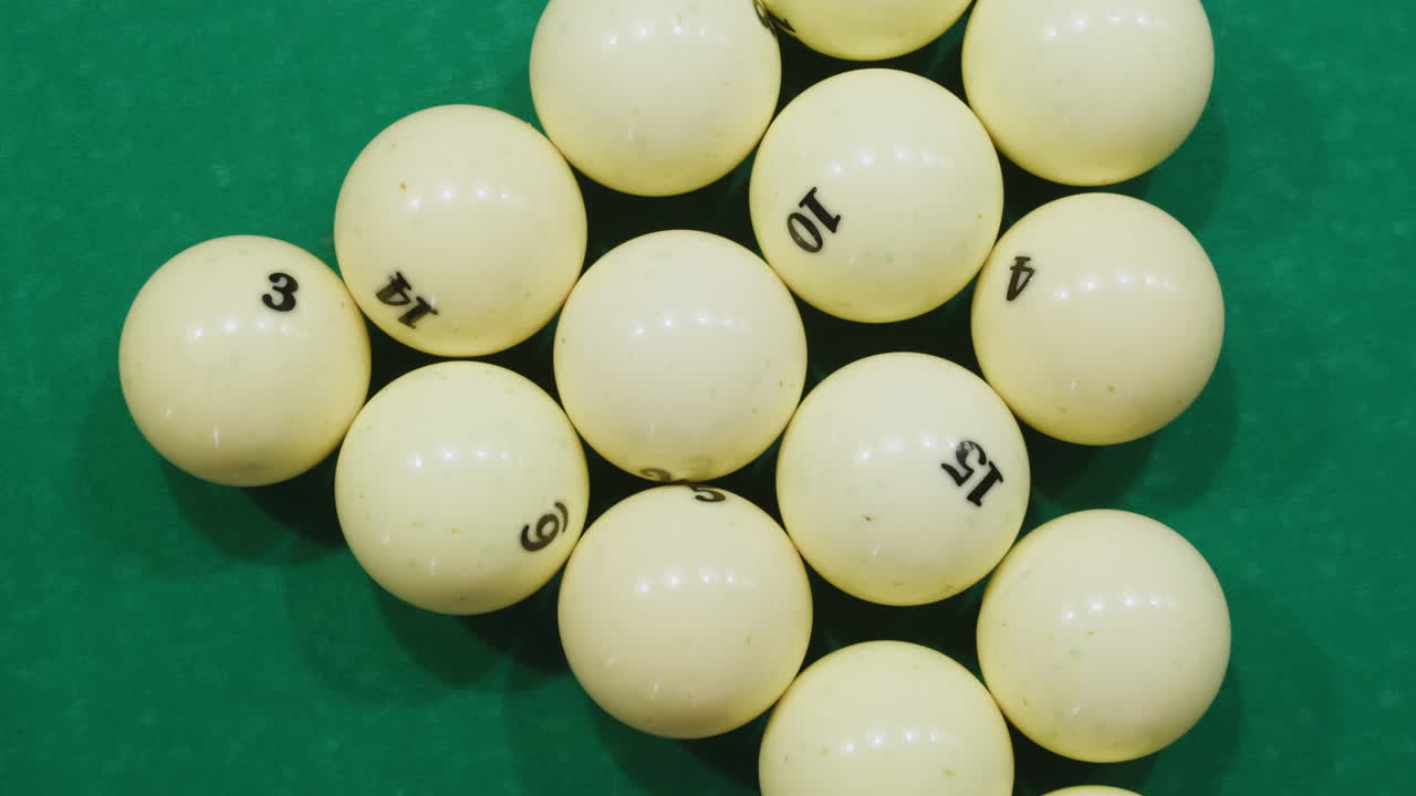 Breaking white pool balls top view on green billiards table for start to play. Russian biliard game, Russian pyramid. Billiard balls with numbers on a pool table. Billiards team sport. High quality 4k footage