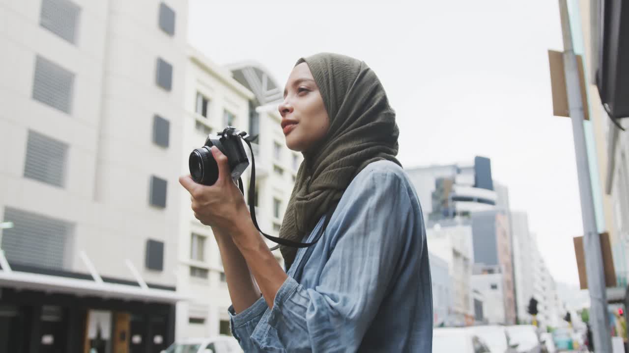 Eine Frau mit Hidschab fotografiert auf der Straße.