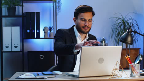 Indian-businessman-freelancer-at-office-workplace-working-on-laptop-computer-sends-online-messages