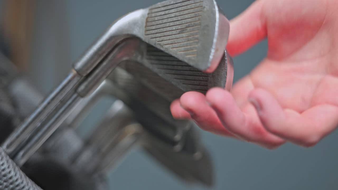 side profile shot of golf clubs being returned back into a golf bag