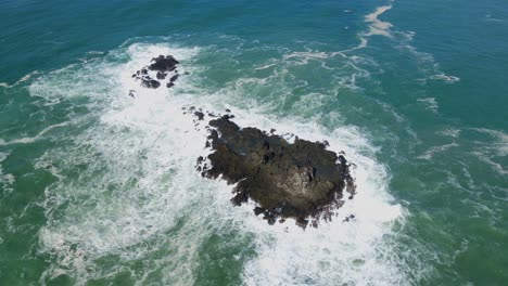 ocean waves and rocky coral island, aerial orbit view