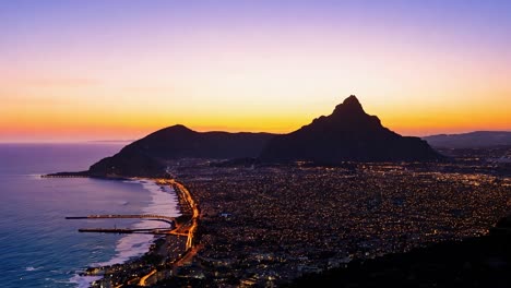 city lights illuminate the landscape as the sun sets over the ocean near lion's head mountain in cape town