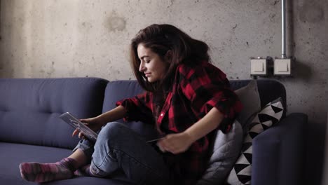 Beautiful-girl-in-her-20's-typing-something-on-laptop-keyboard-while-she-is-chilling-out-on-the-sofa