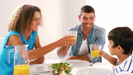 Nette-Familie,-Die-Zum-Mittagessen-Mit-Orangensaft-Anstößt