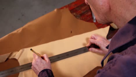 shoemaker marking a piece of leather with pencil