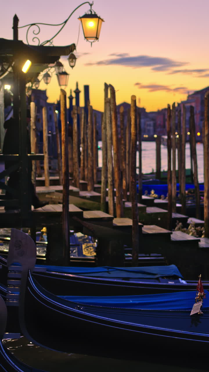 Multiple gondola boats docked on the side of the Grand Canal in Venice City, Italy at sunset. Vertical, Venice, Italy