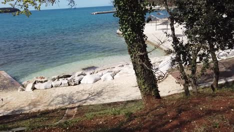 Driving-Past-Polidor-Campground-Past-Beach-And-Parasols-With-Adriatic-Sea-In-The-Background,-Croatia