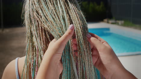 A woman admires her daughter&#039;s Afro-braids, holds them in her hand. Stand by the pool