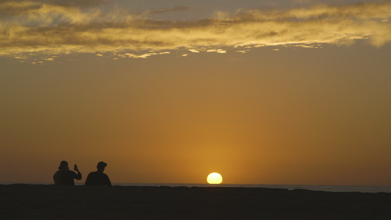 A couple silhouetted by the sunset on Venice Beach in Los Angeles