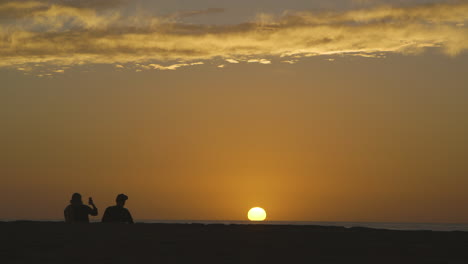 a couple silhouetted by the sunset on venice beach in los angeles