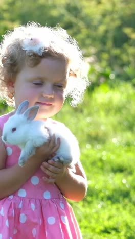 a little girl with a bunny in her hands. vertical video