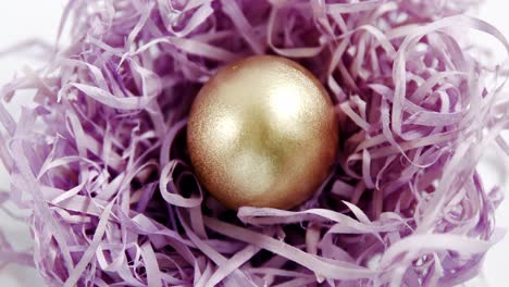 Golden-Easter-egg-in-the-paper-nest-on-white-background