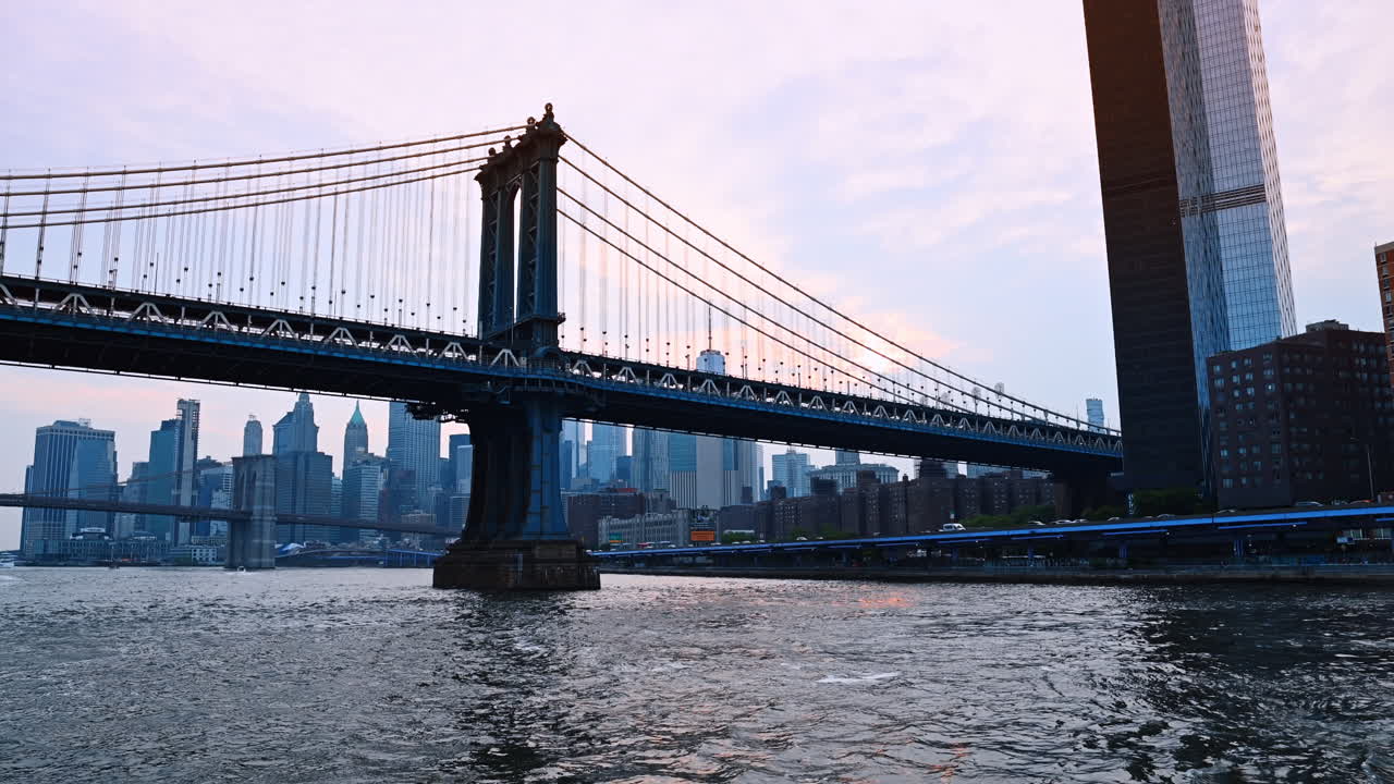 New York, USA, 15 aprile 2026: Ponte di Manhattan sull'East River all'alba. Il Ponte di Manhattan visto dall'East River con lo skyline di Lower Manhattan sullo sfondo durante la luce del primo mattino