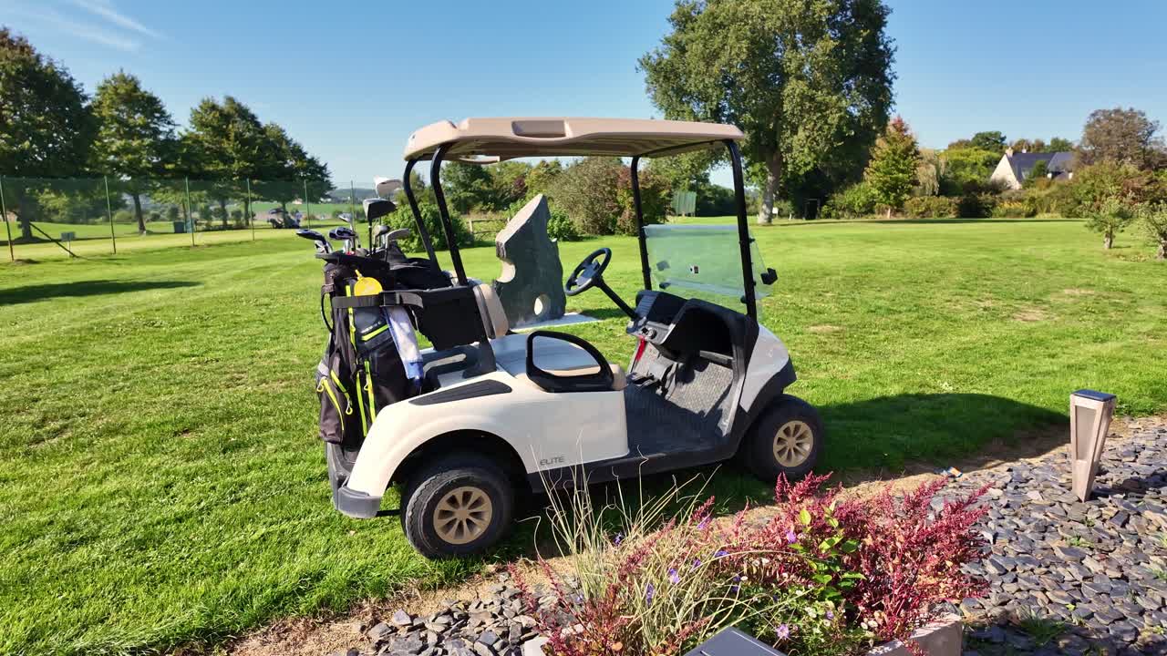 Carrinho de golfe elétrico vazio com dois sacos de tacos estacionado na grama verde de um campo de golfe ensolarado