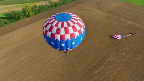 Aerial-top-down-shot-of-hot-air-balloon-With-american-flag-flying-over-countryside-field-in-summer---Amish-Country