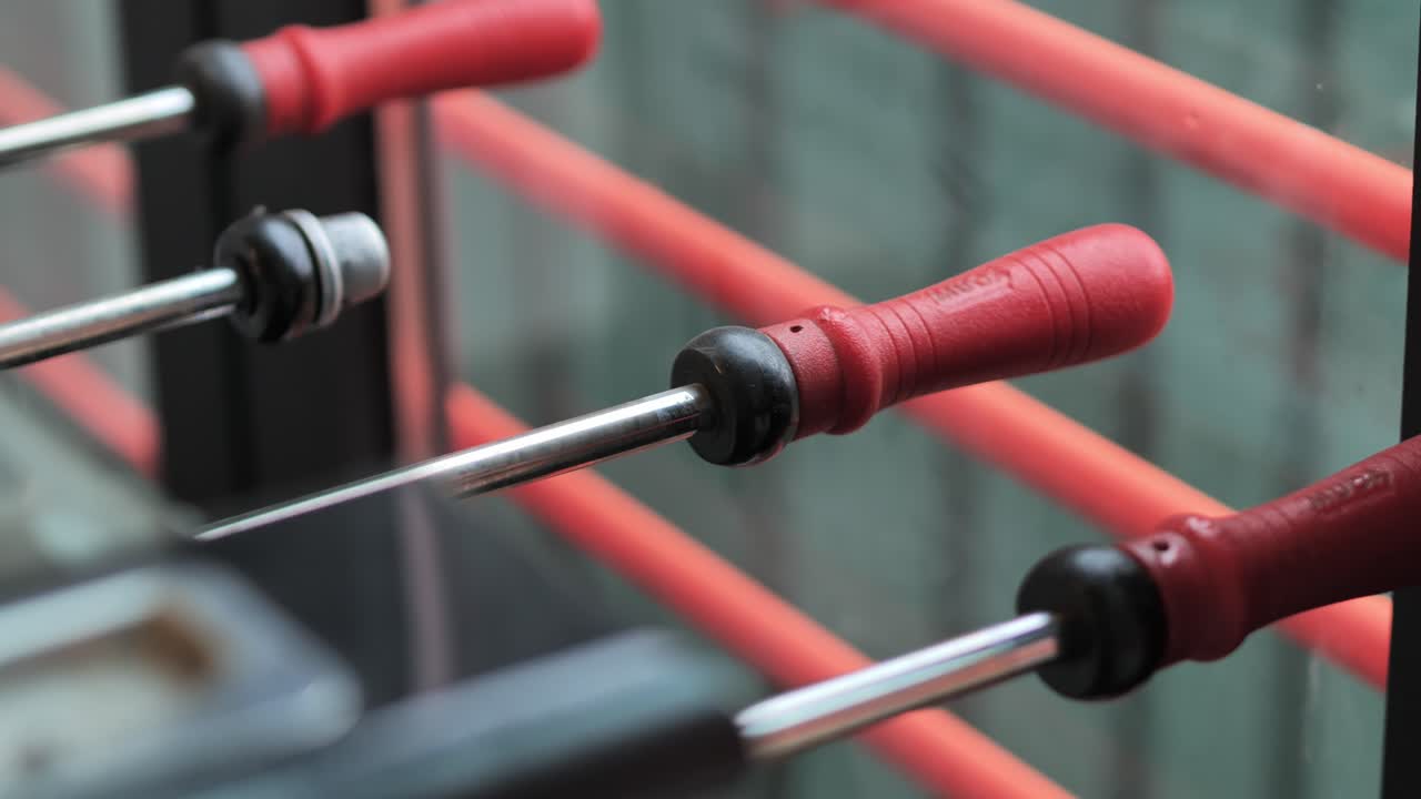 Close-up sliding shot of foosball table handles filmed with steady movement - 4K.