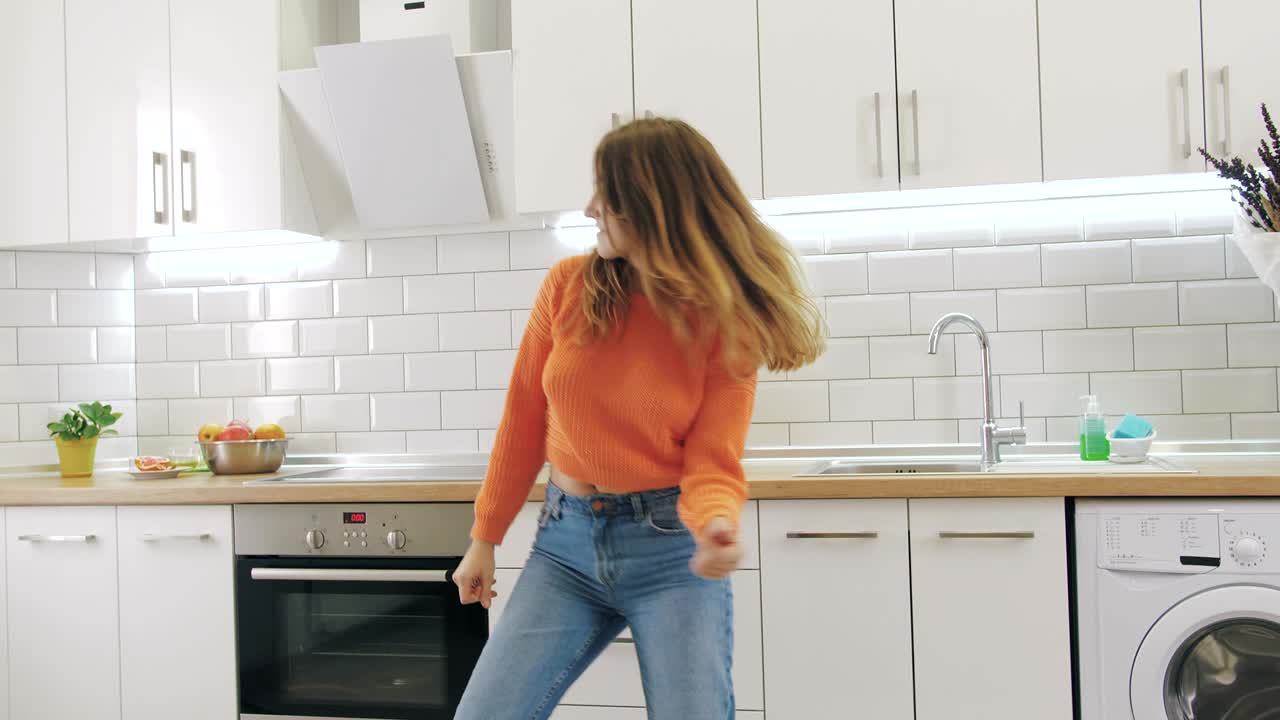 Giovane donna felice che balla in cucina e si diverte