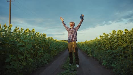 happy farmer celebrating in a sunflower field