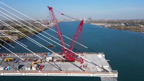 Industrial-machines-constructing-bridge-over-Detroit-river,-aerial-view