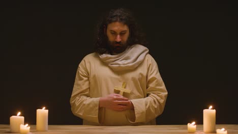 fotografía de estudio de un hombre vestido con túnicas que representan la figura de jesucristo sosteniendo una cruz de madera 2